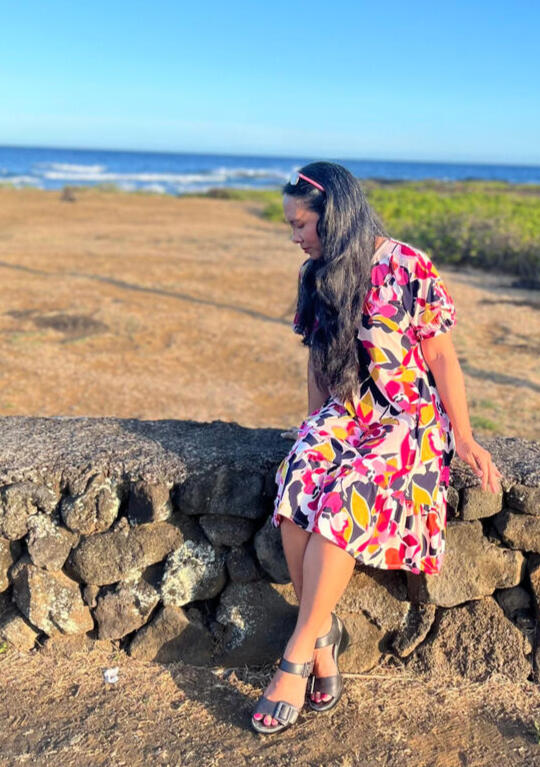 Photo of Joan Obra at her family's coffee farm on Hawai'i Island. She's standing next to coffee branches studded with blooming white flowers.